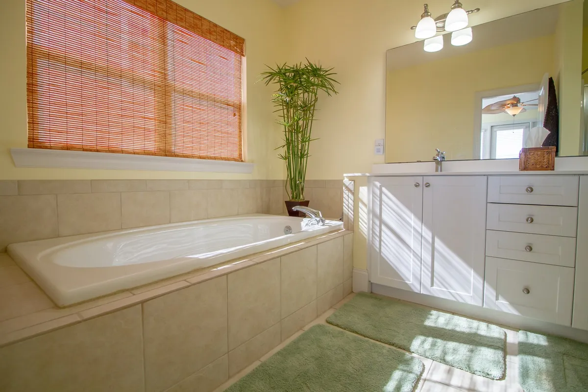 A calm and elegant bathroom with a garden tub set beside a window, a double vanity, and a bamboo plant adding a touch of spa-like relaxation. Morning light softly fills the room, emphasizing luxury and peace.